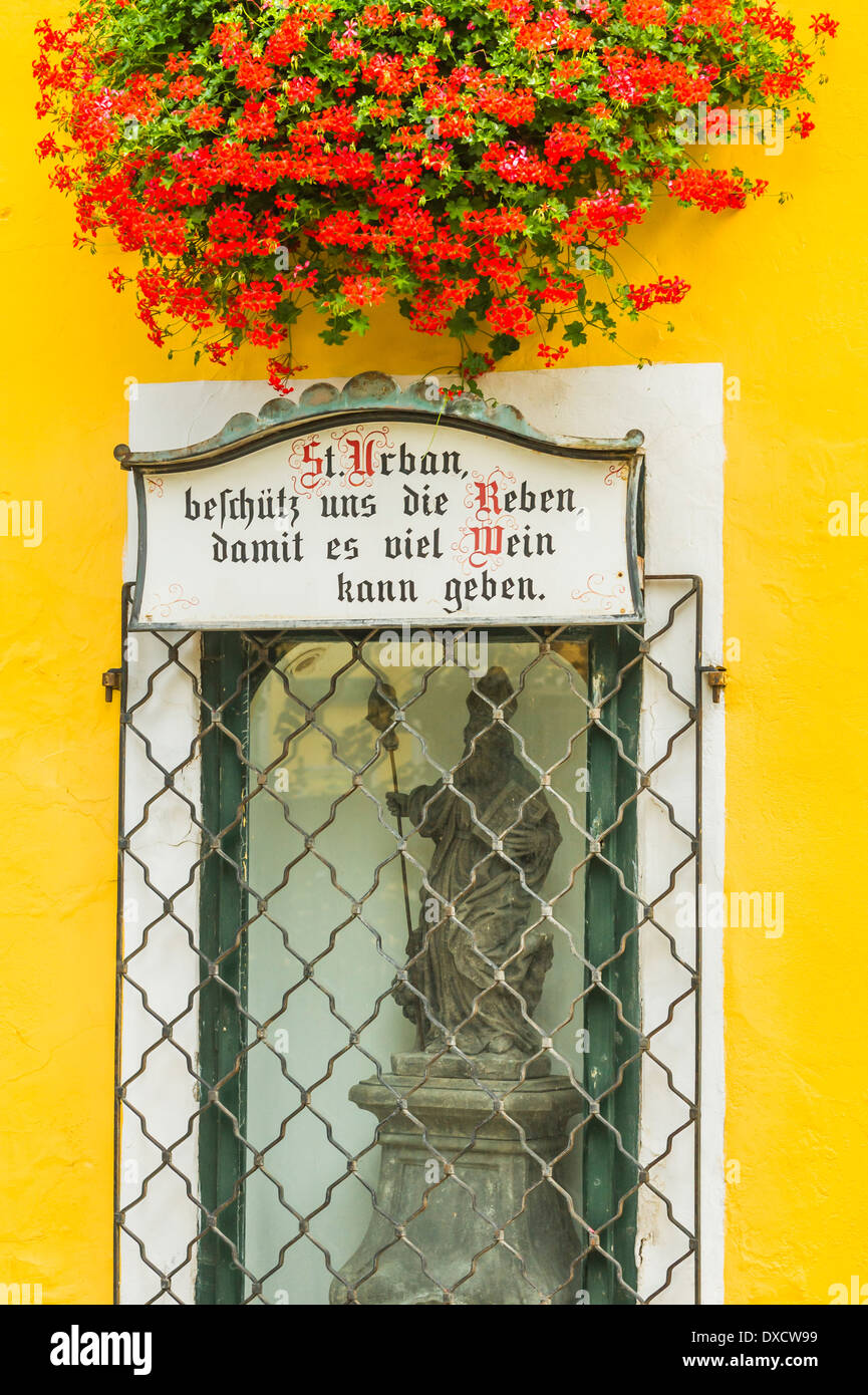 flower decked alcove at the building of the reinprecht winery with a statue of st. urban and a plaque Stock Photo