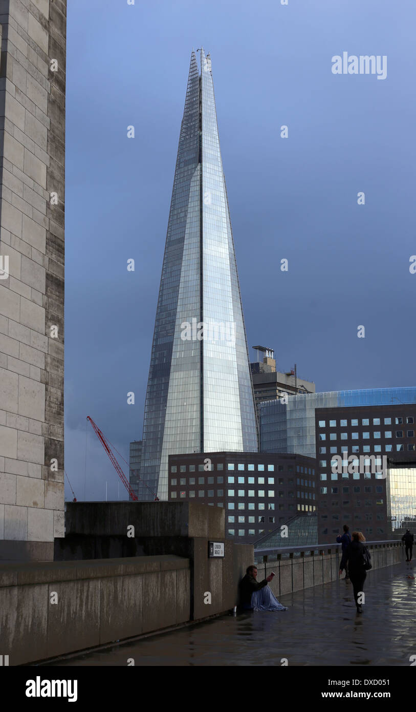 Poor begging near London's building, The Shard highlighting the differences in richness of this world. Unfair New World Order. Stock Photo