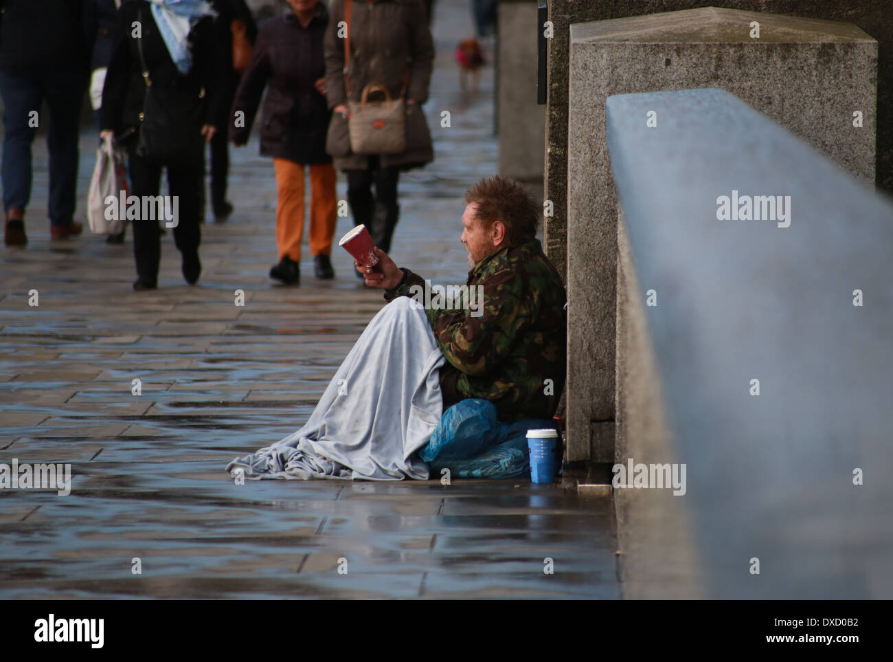 Beggar in London Bridge after a hale storm Stock Photo