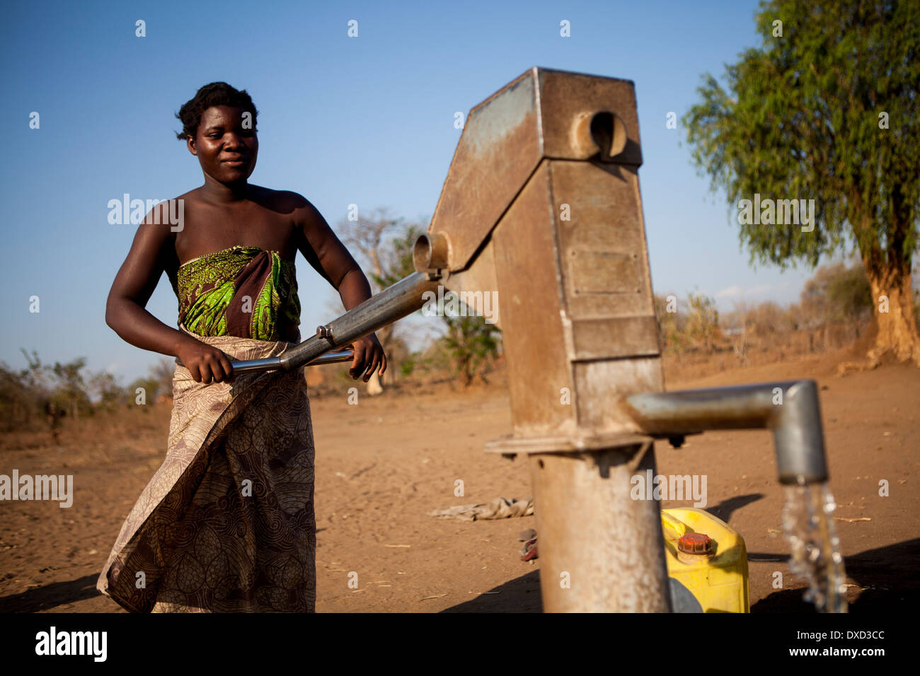 Africa woman pumping water at a stand pipe Stock Photo