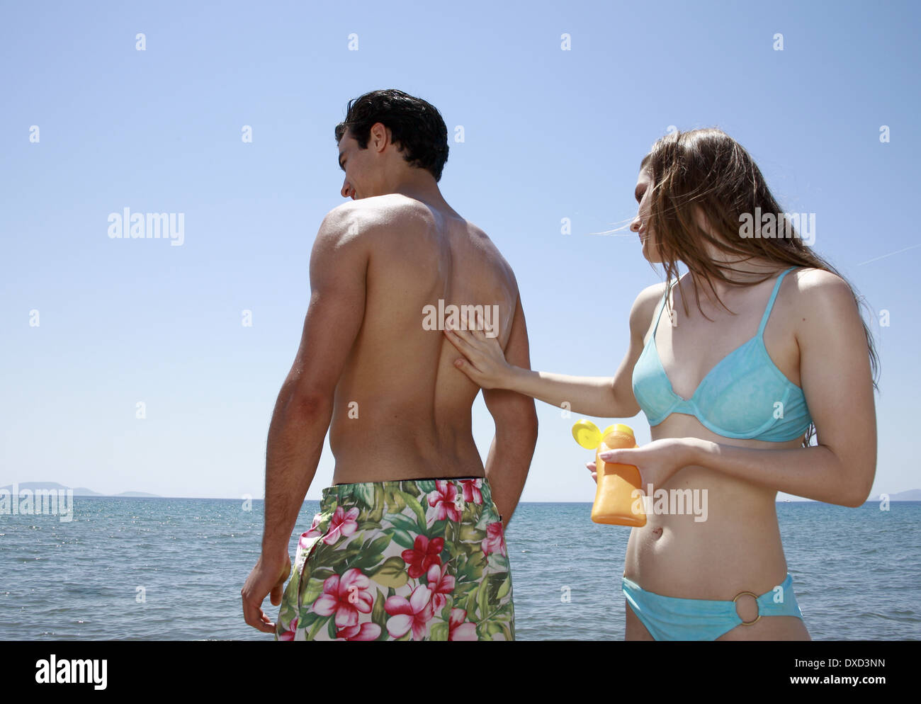 Female young adult applying suntan lotion on male's back Stock Photo Alamy