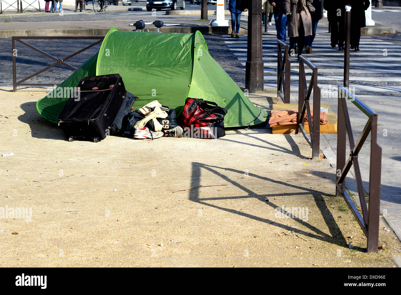Homeless people tent in the middle of Paris at the road side with unrecognizable people passing by in their usual city rush Stock Photo