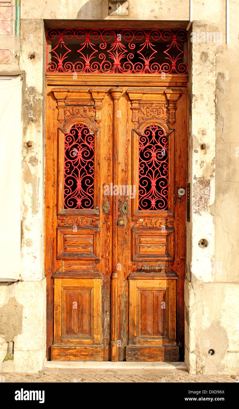Old entrance door made of carved wood and painted in red metal decorations. Stock Photo