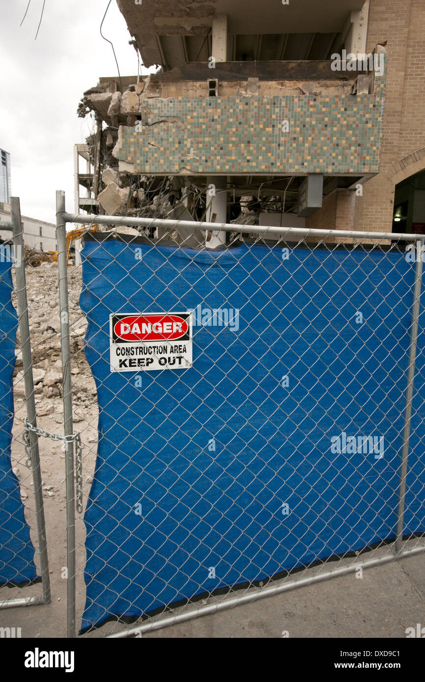 Sign saying Danger Construction area keep out, posted on chain link fence outside of a building demolition area in Austin, Texas Stock Photo