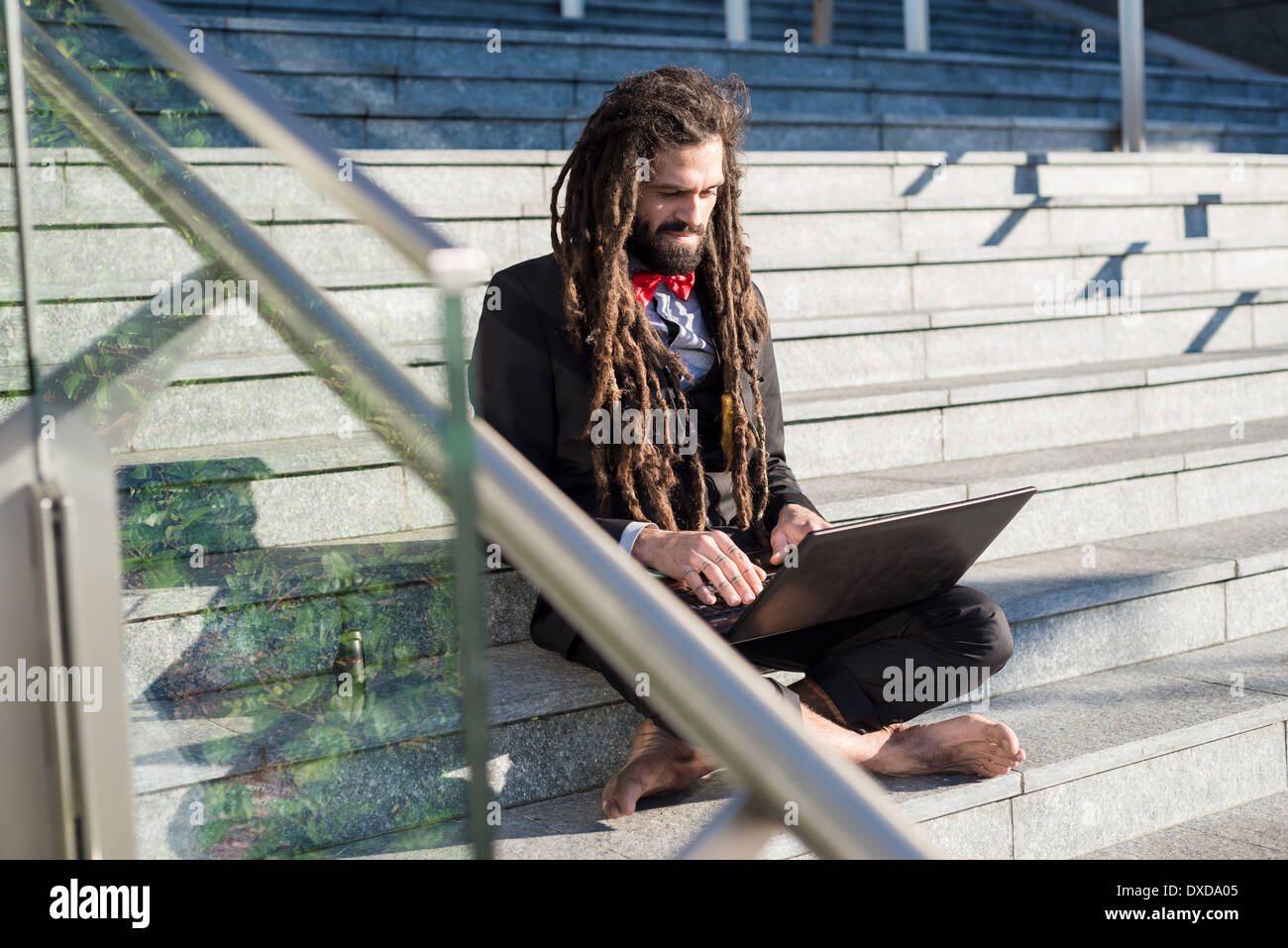 Stylish elegant dreadlocks businessman using notebook in business landscape Stock Photo