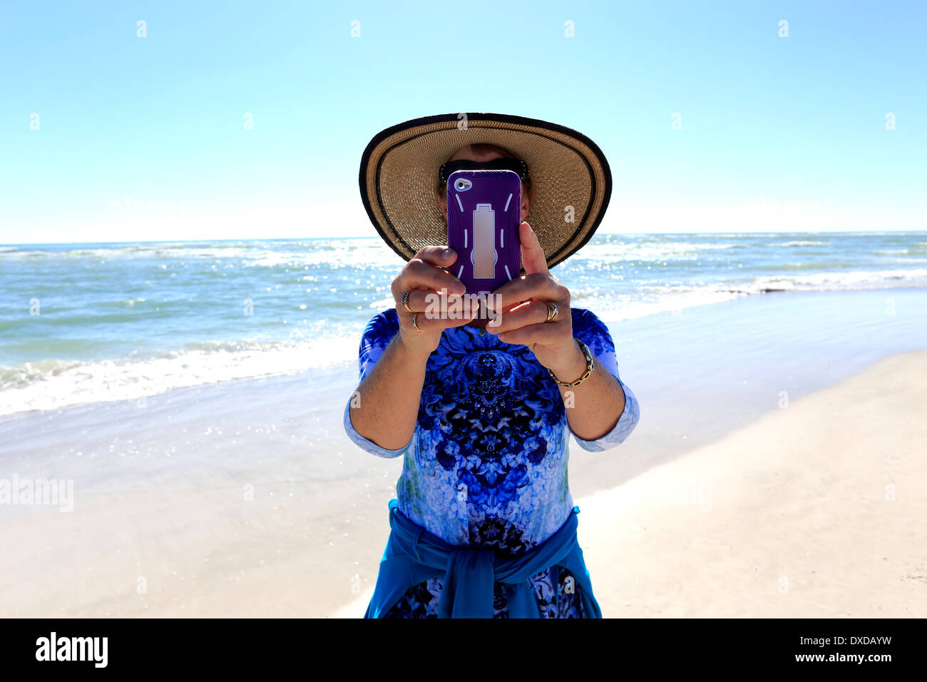 A woman taking pictures or photographs at a beach with an IPod or IPhone or camera phone Stock Photo