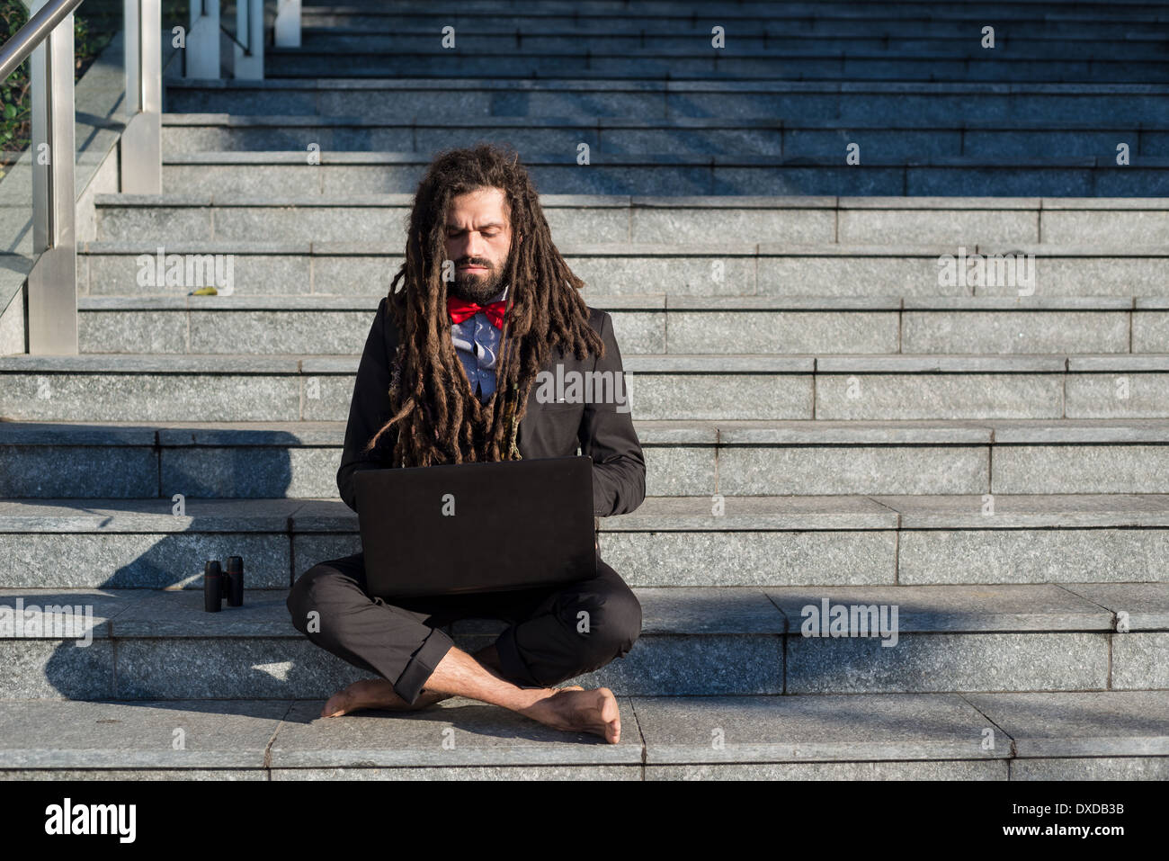 Stylish elegant dreadlocks businessman using notebook in business landscape Stock Photo