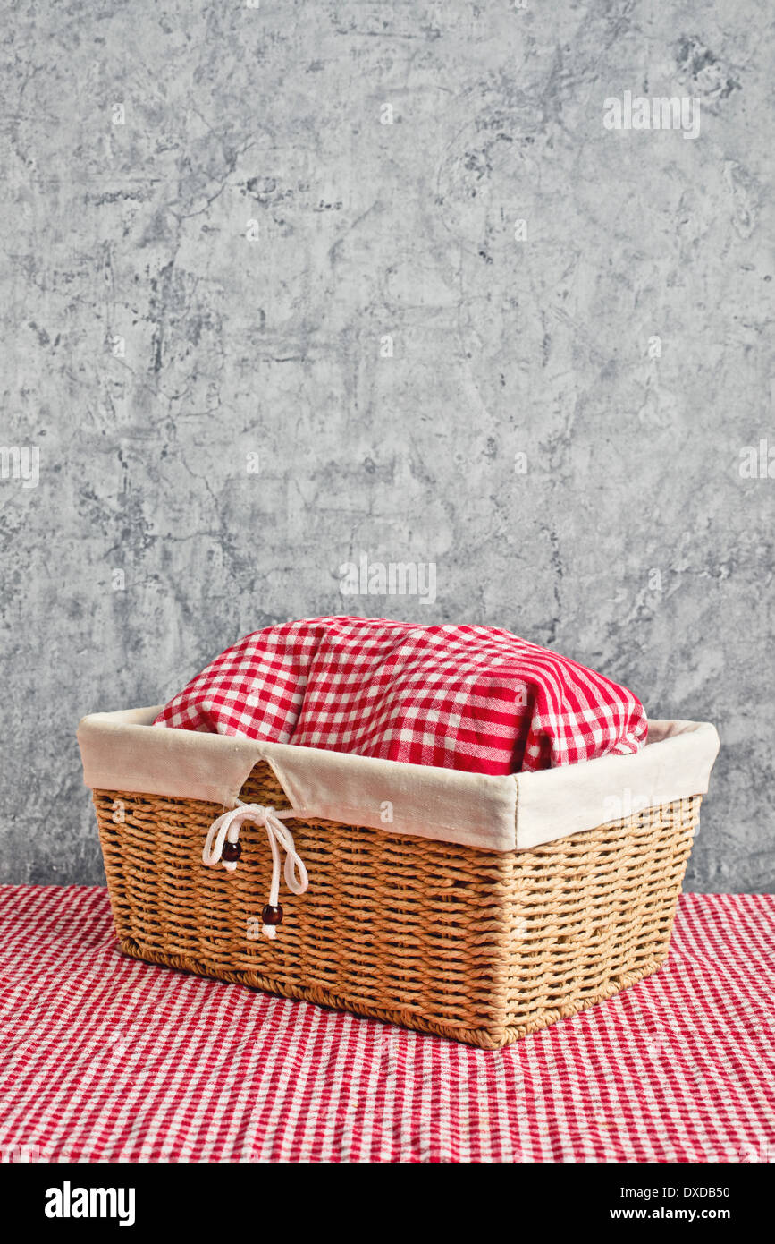 Bread in wicker basket covered with rag on kitchen table with copy
