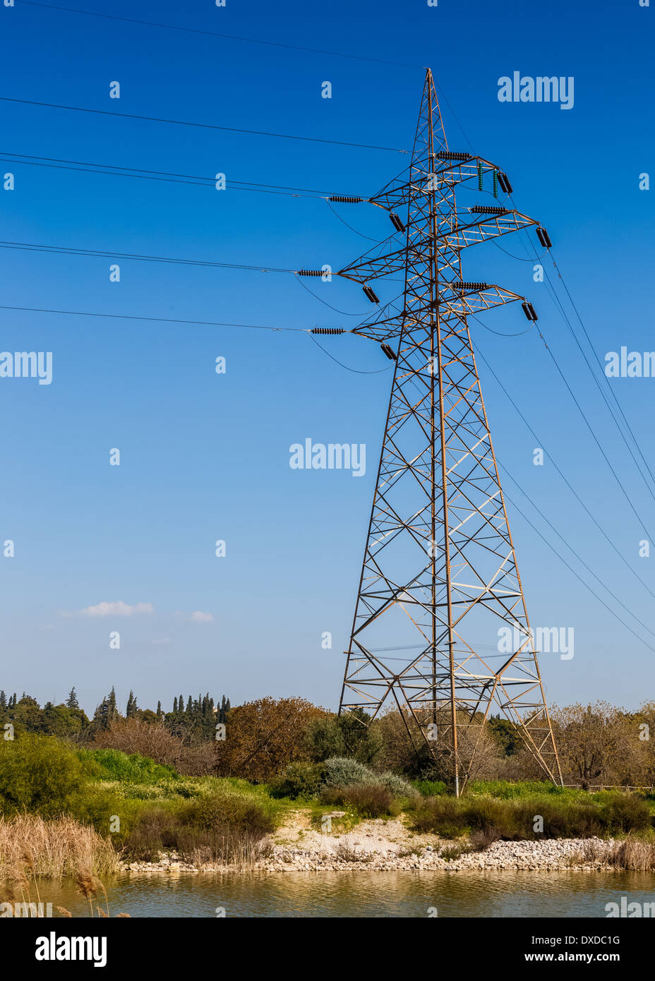 Transmission tower and power lines against blue sky and clouds Stock Photo