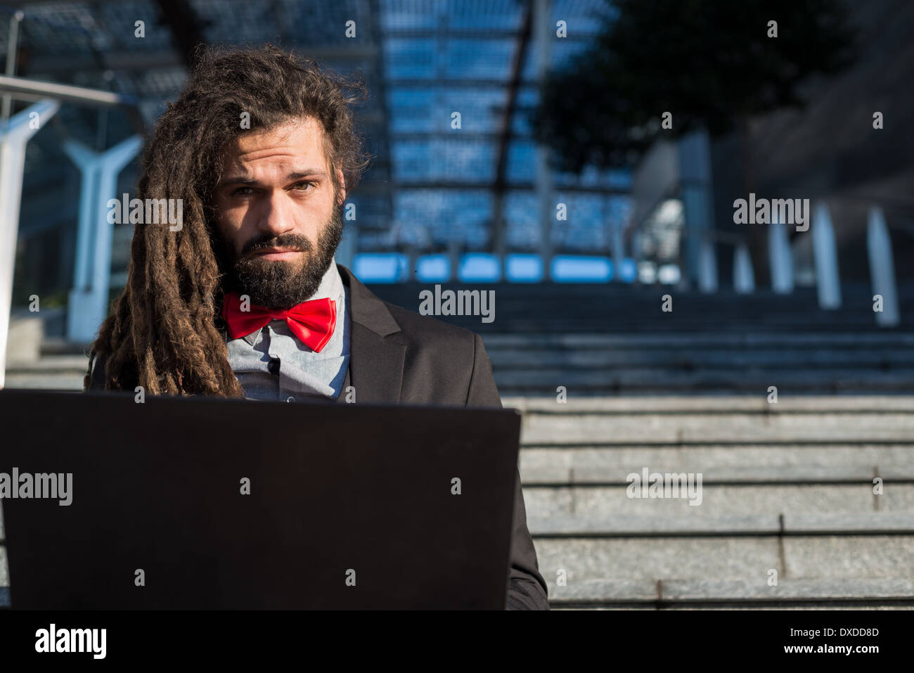 Stylish elegant dreadlocks businessman using notebook in business landscape Stock Photo