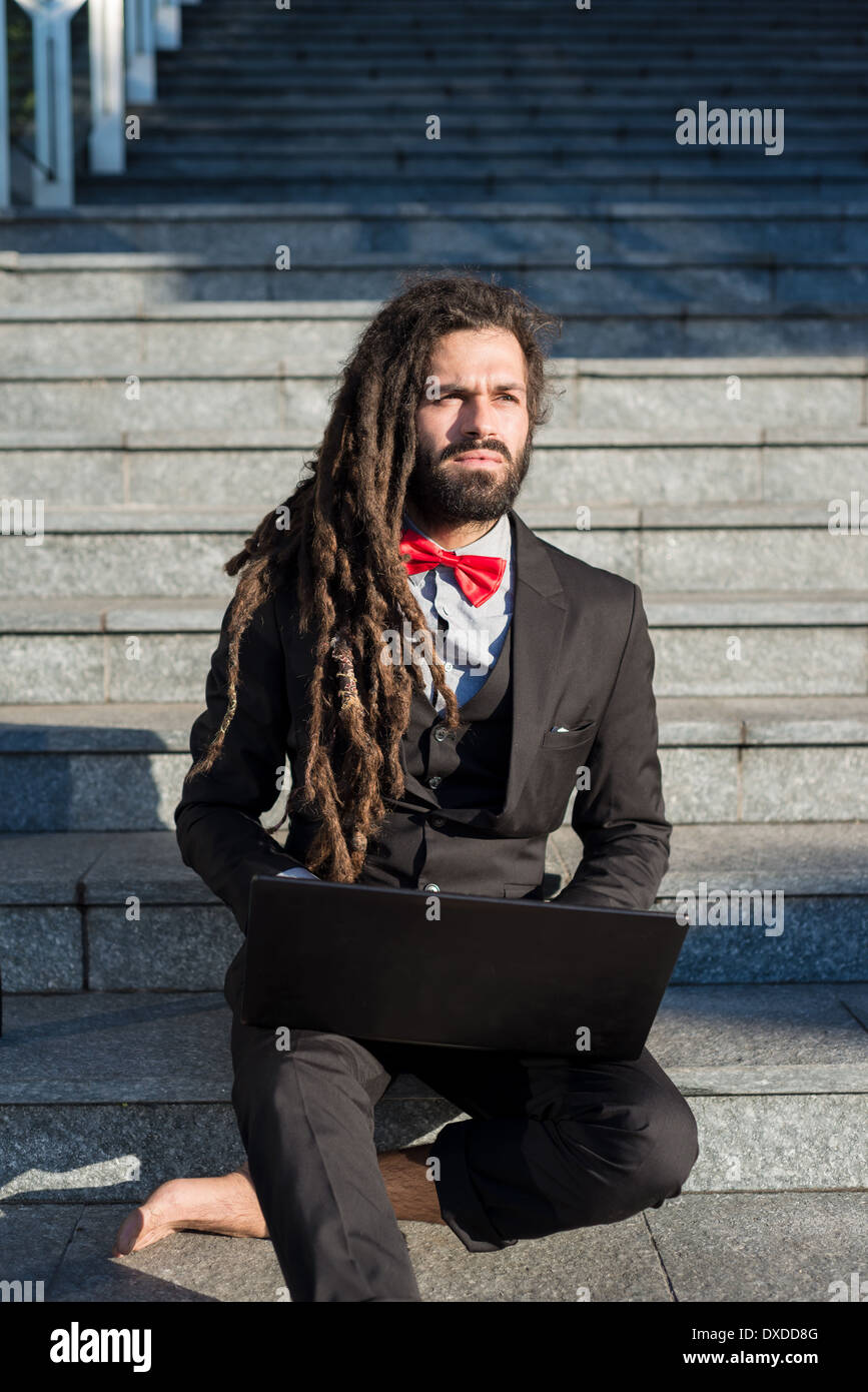 Stylish elegant dreadlocks businessman using notebook in business landscape Stock Photo