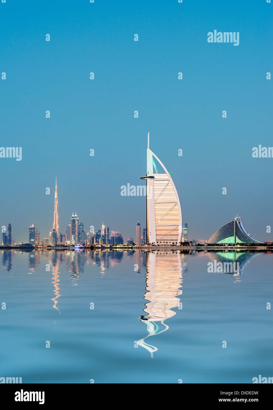 Night skyline  to luxury Burj al Arab hotel and city of Dubai with Burj Khalifa tower in distance in United Arab Emirates Stock Photo