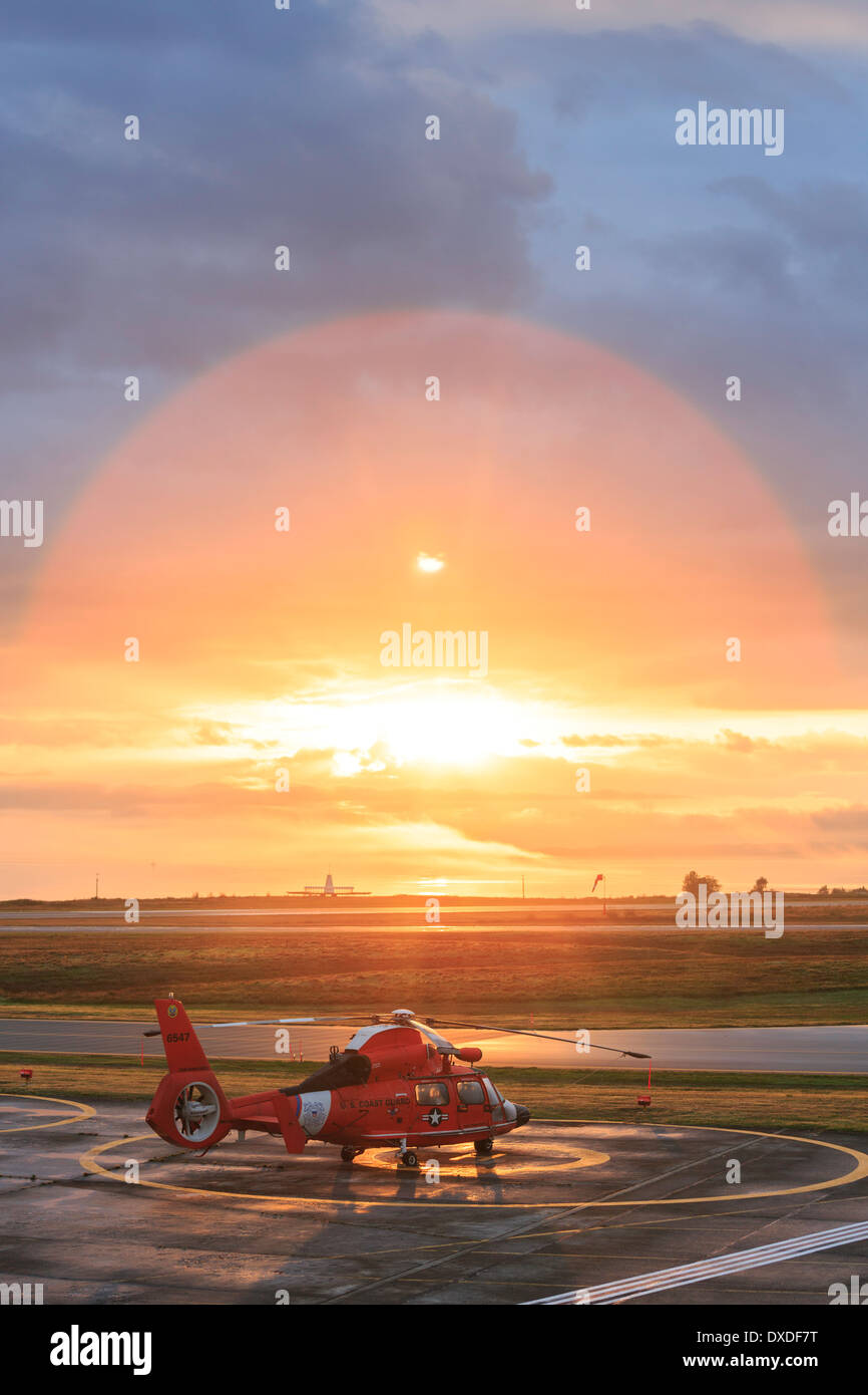 A US coast guard helicopter on a helipad during sunrise. Stock Photo