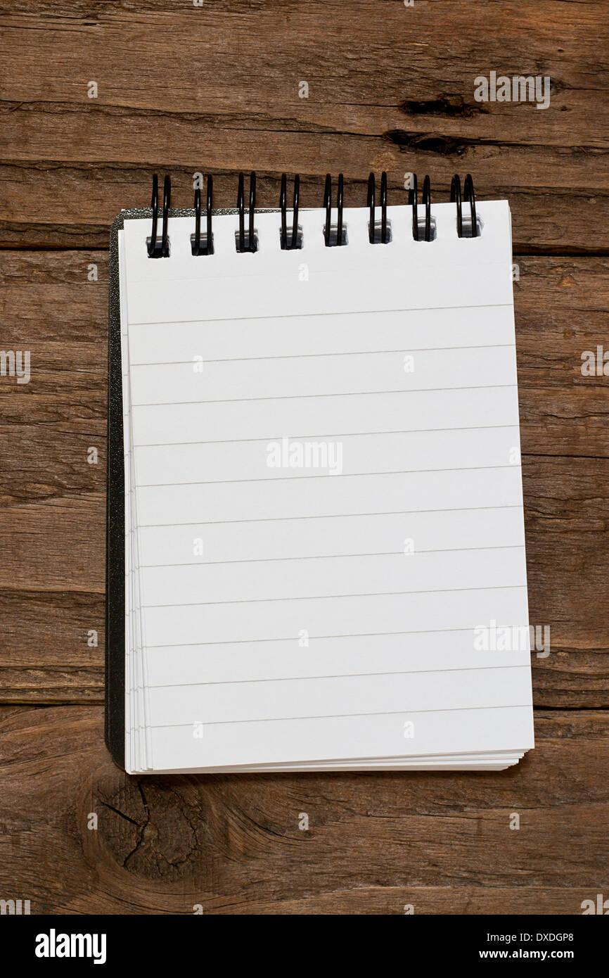 Small pocket sized notepad on a rustic wooden background with blank space for inserting your own message or note. Stock Photo