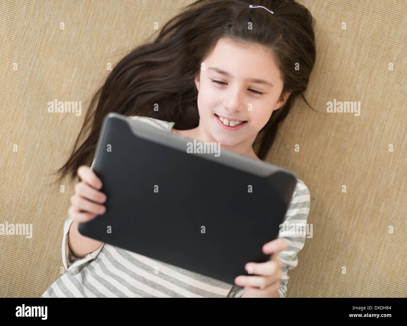 Girl (8-9) lying on floor using tablet pc Stock Photo