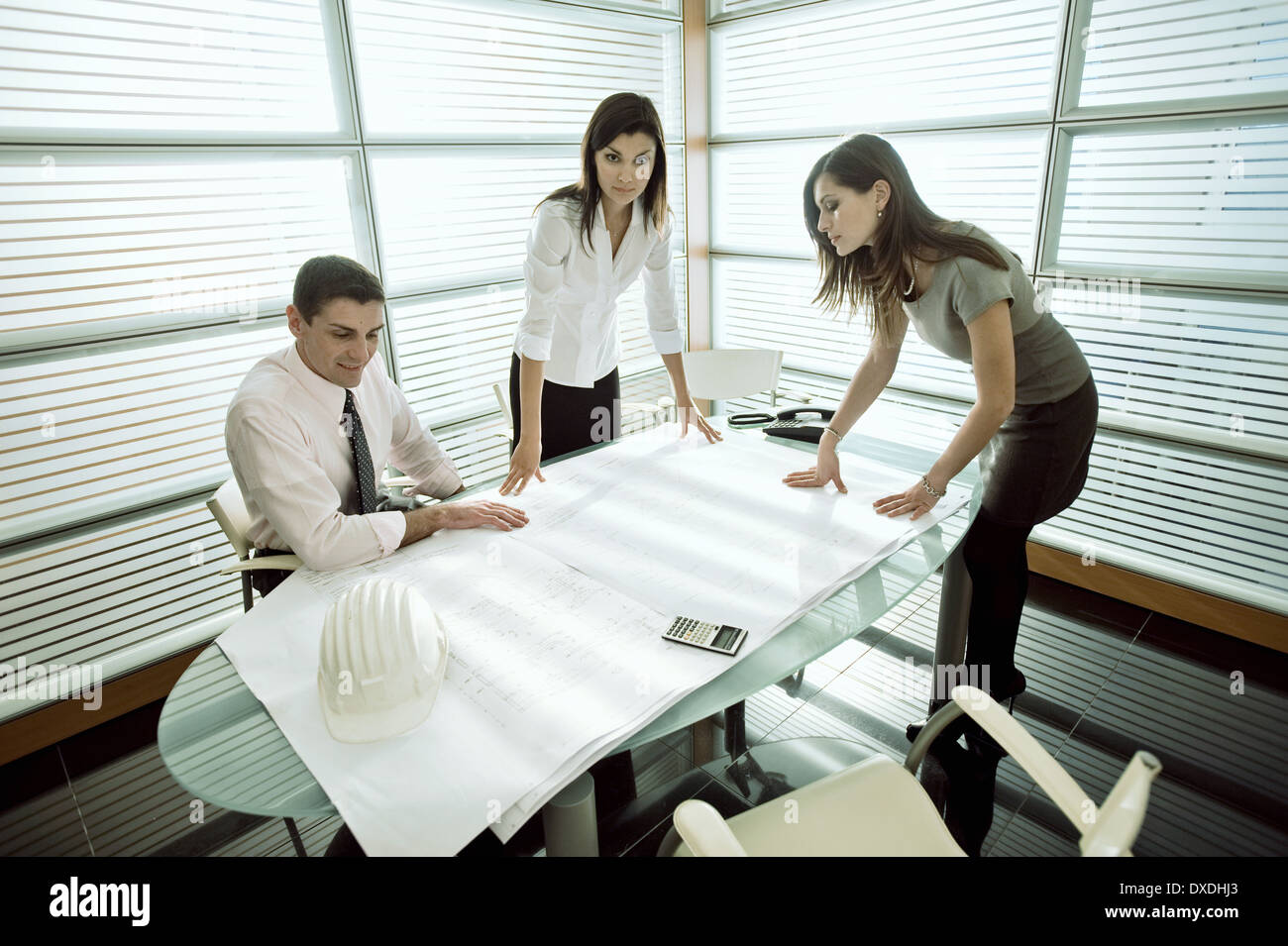 Professionals looking at architectural plans on desk Stock Photo