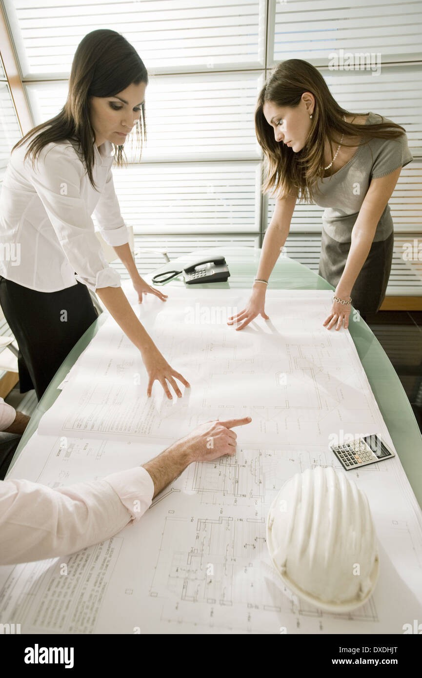 Professionals looking at architectural plans on desk Stock Photo