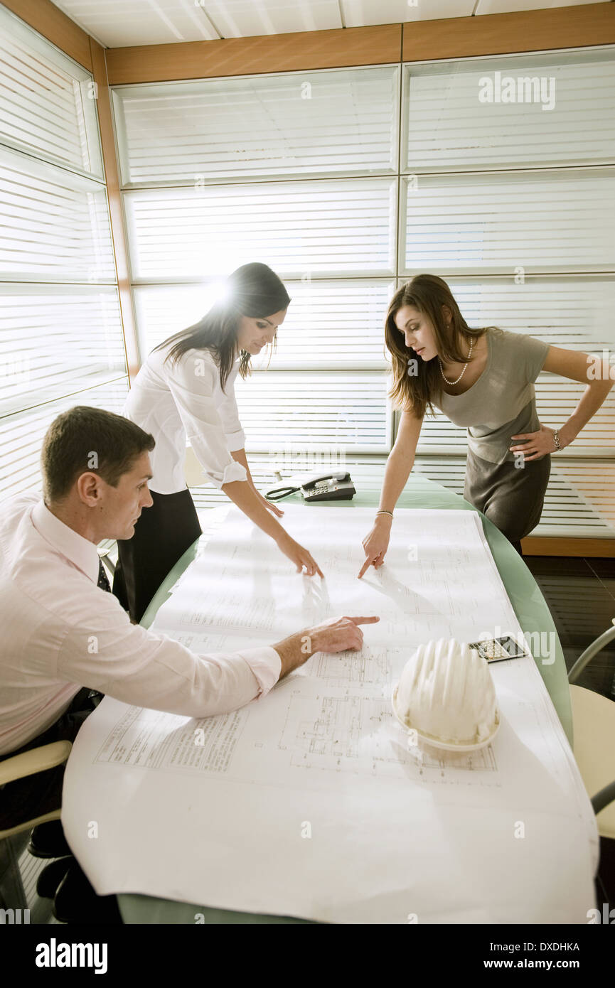 Professionals looking at architectural plans on desk Stock Photo
