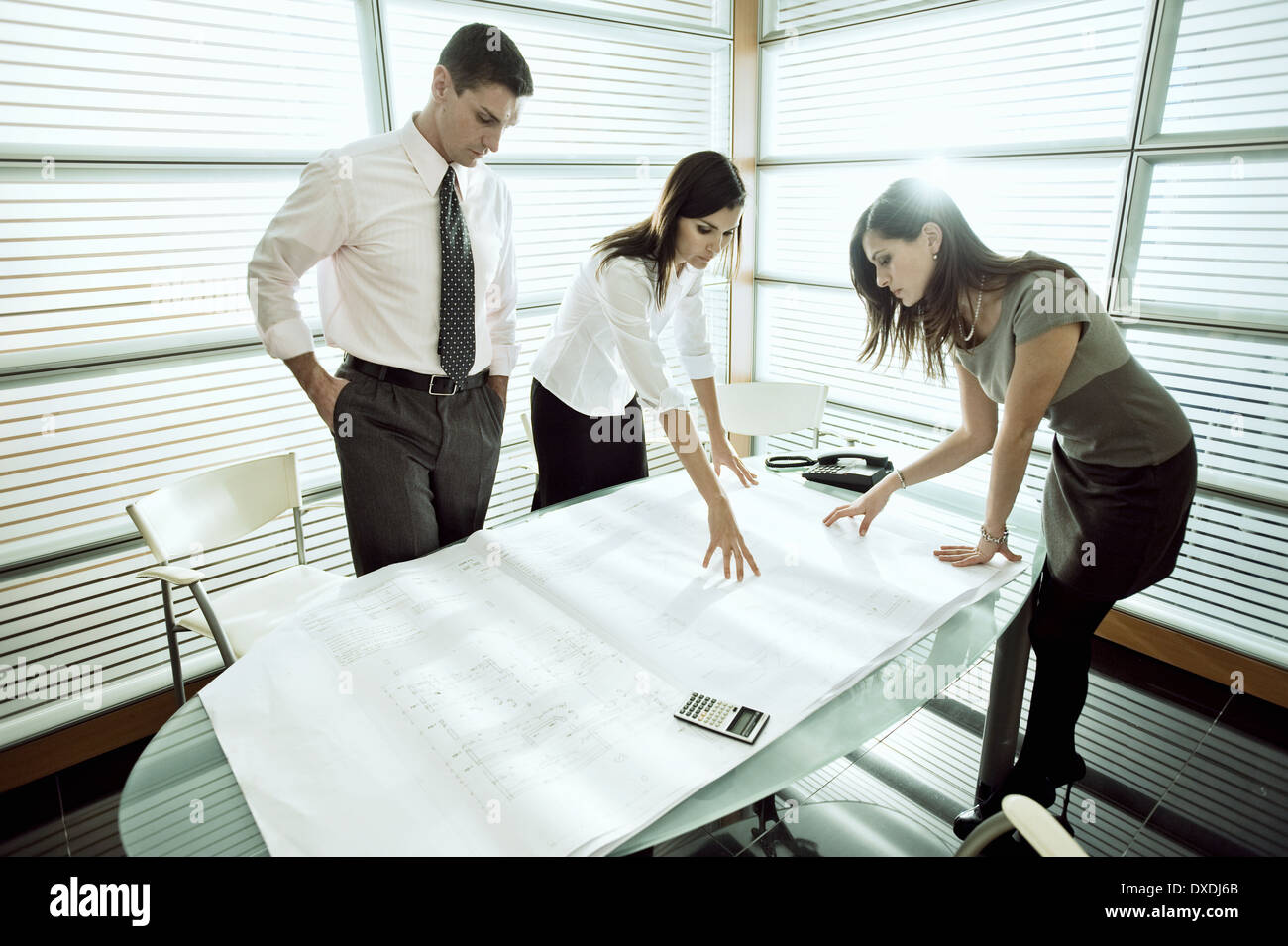 Professionals looking at architectural plans on desk Stock Photo