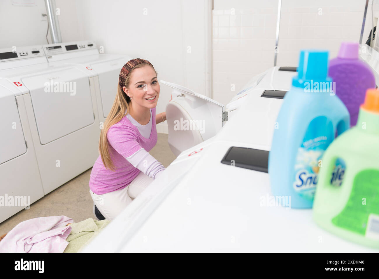 Woman loading laundry into washing machine Stock Photo