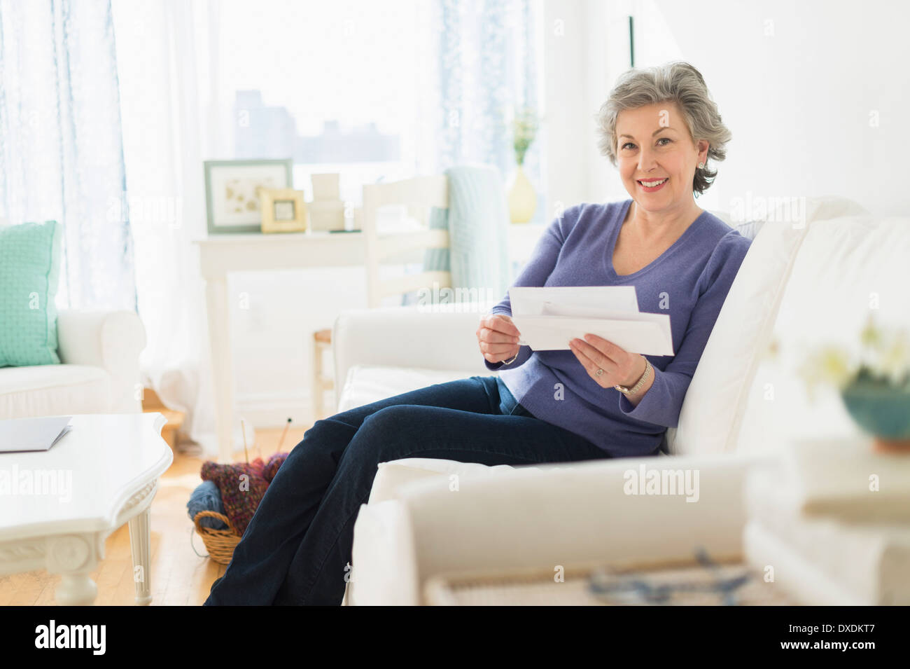 Woman sitting on coach reading letters Stock Photo Alamy