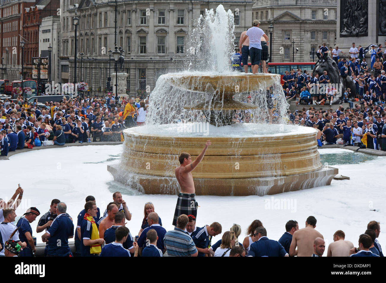 Scottish football fans on top of fountain crowds around Trafalgar Square before international match at Wembley between England & Scotland London UK Stock Photo