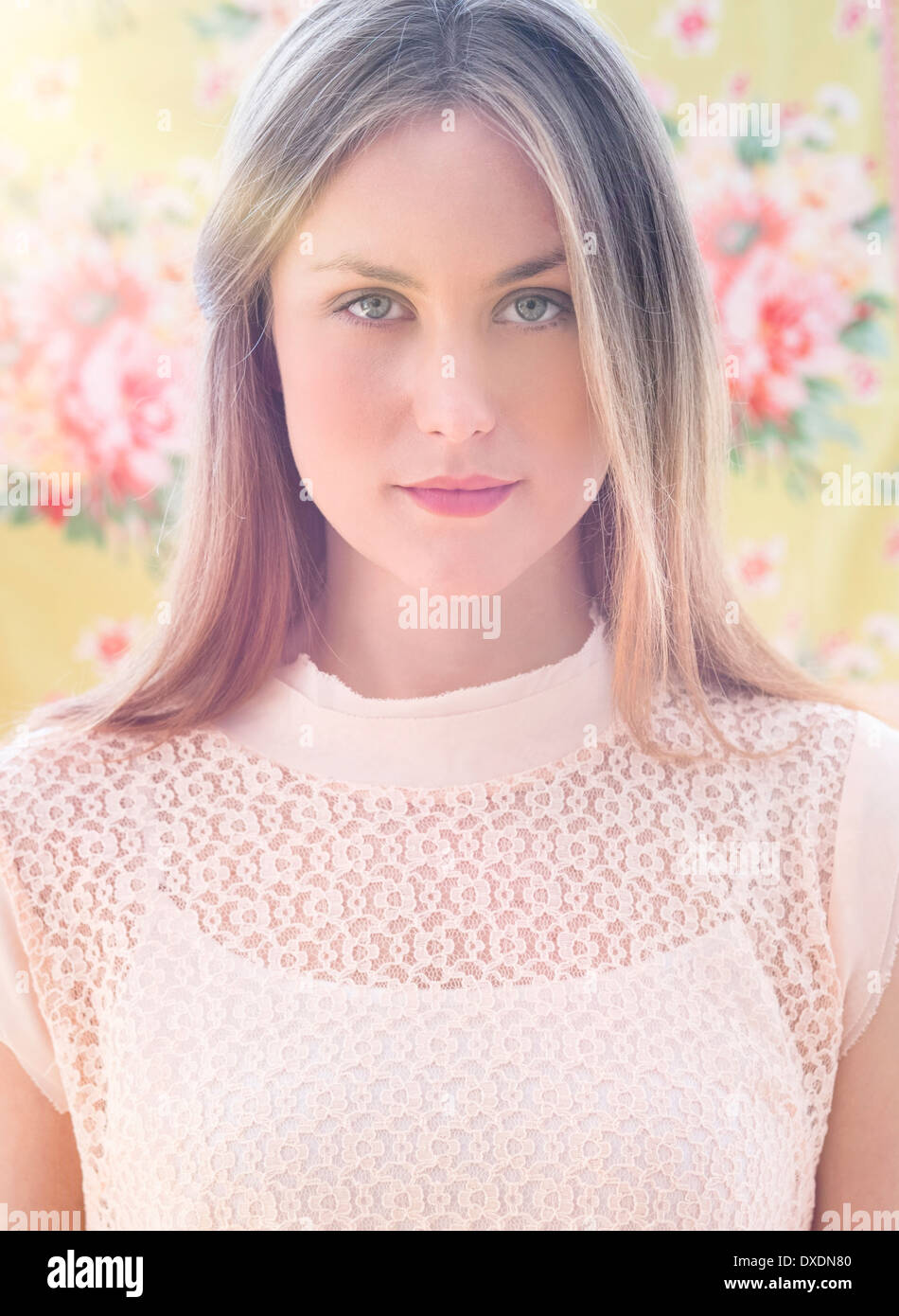 Portrait of young woman in front of floral wall paper Stock Photo - Alamy