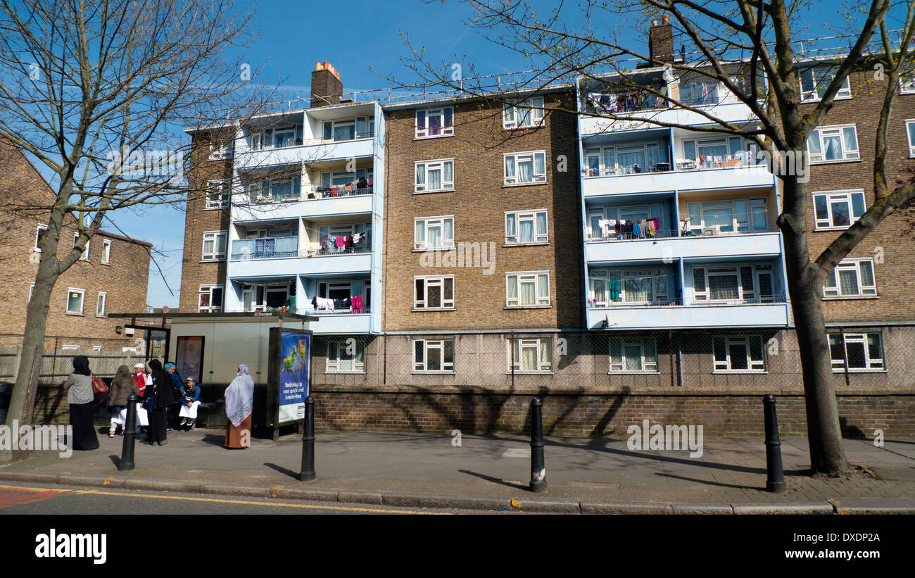 Muslim women waiting at a bus stop by a block of flats on Globe Road ...