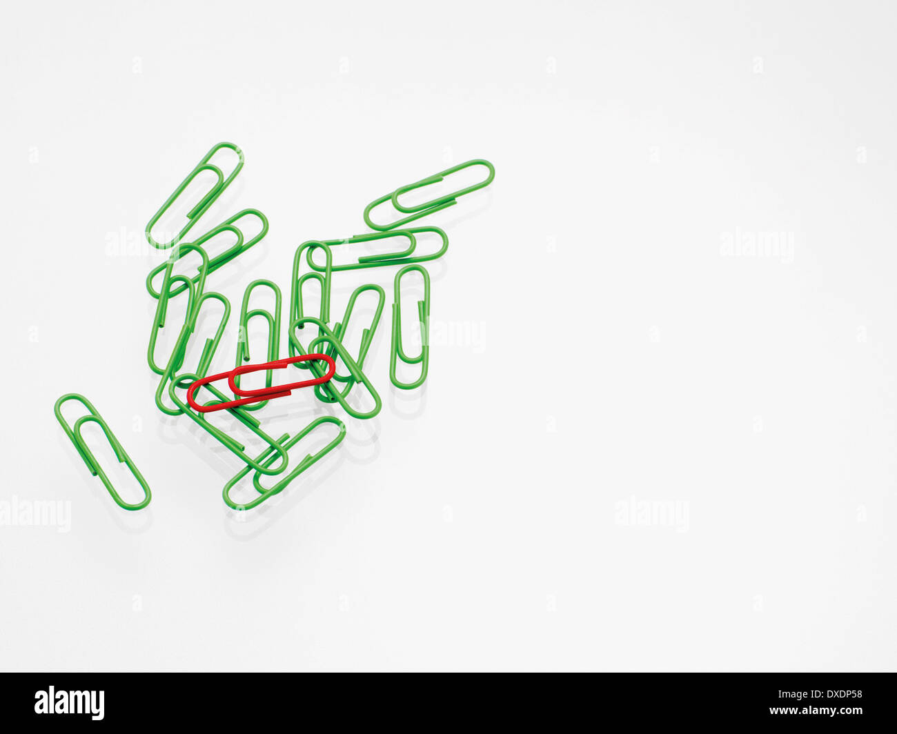 Green and red paper clips on white background, studio shot Stock Photo