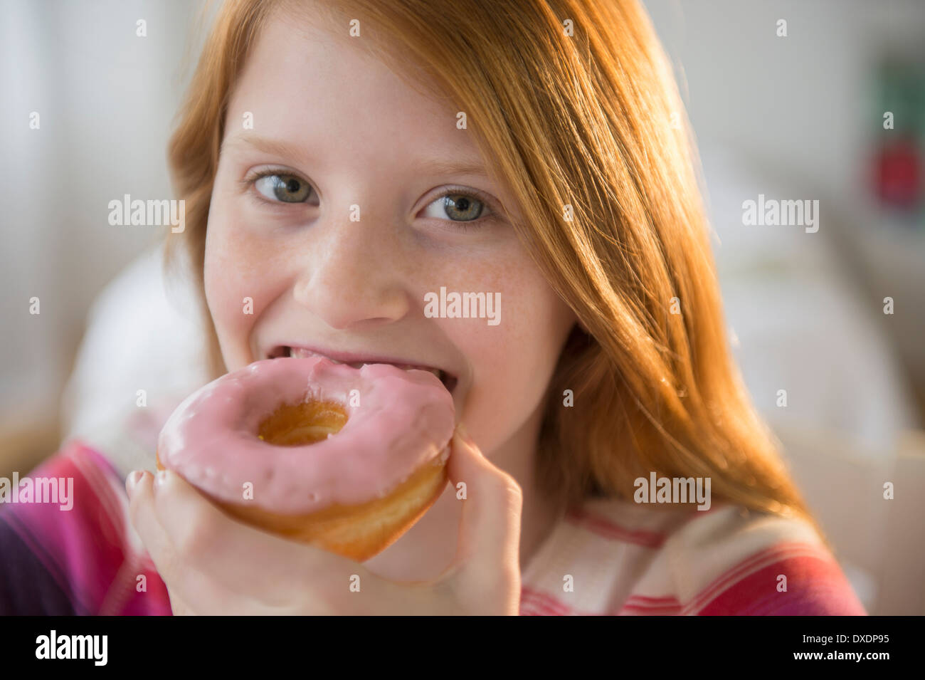 Portrait of girl (12-13) eating doughnut Stock Photo
