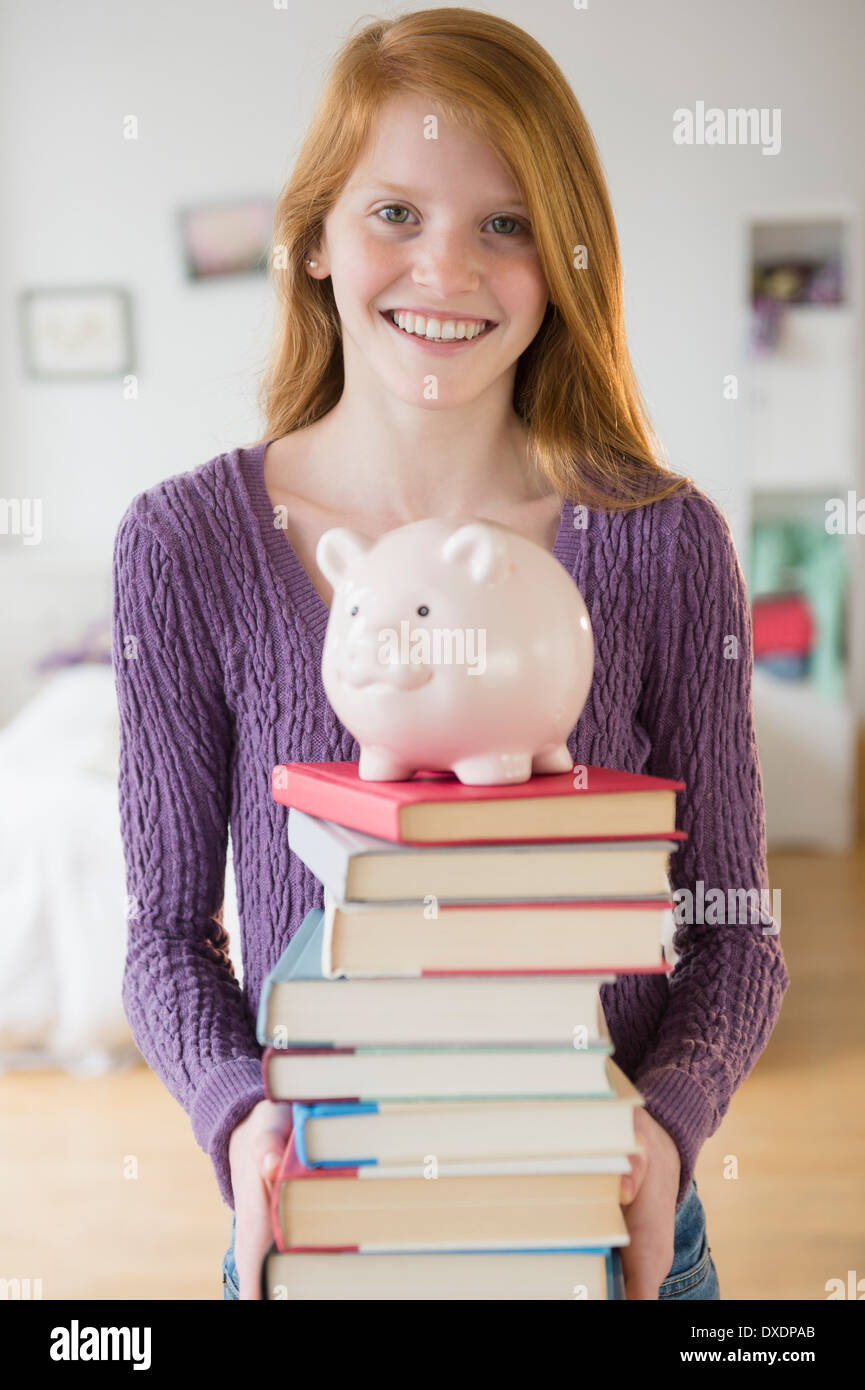 Portrait of college girl holding books with blurred students standing ...