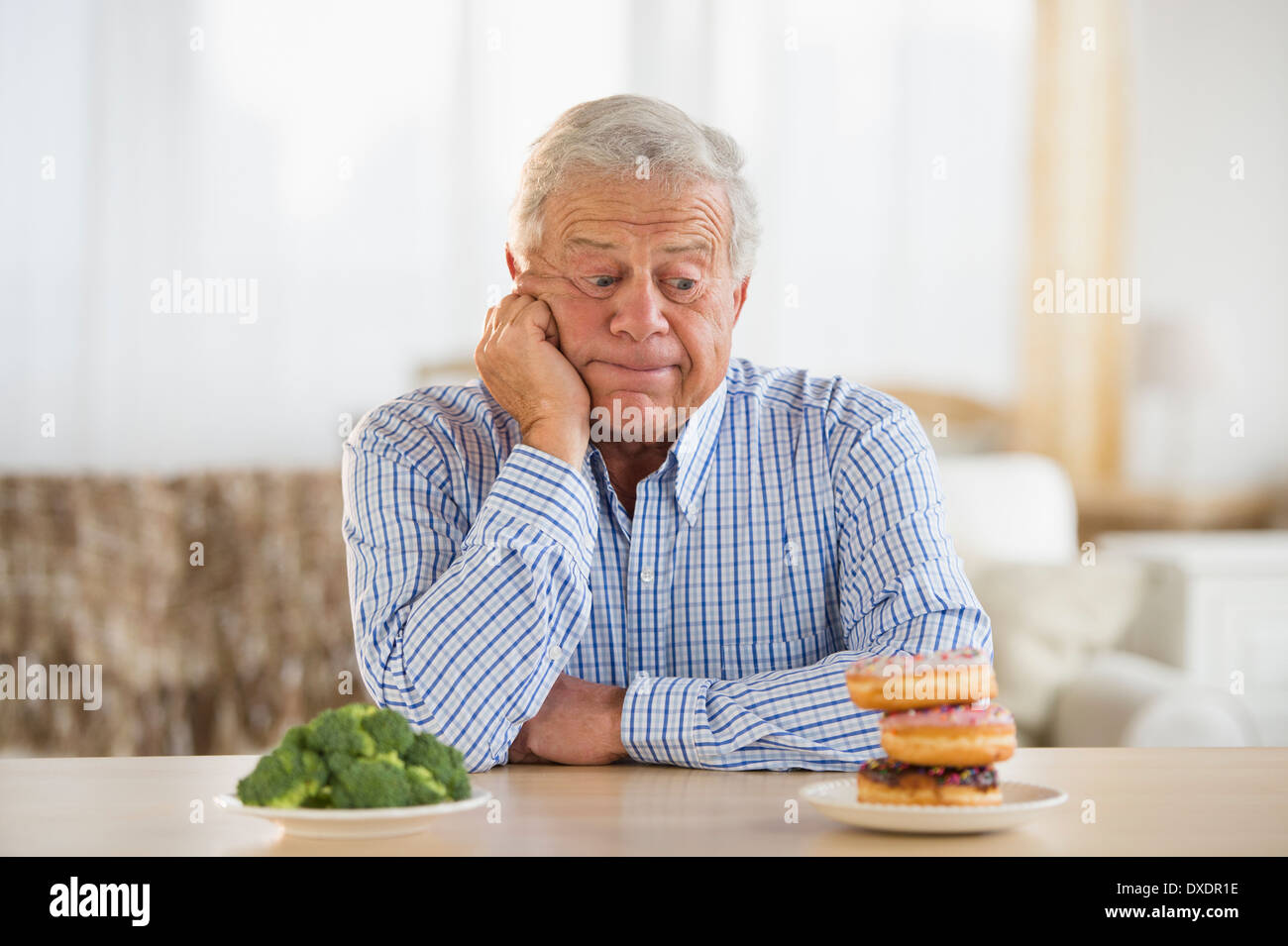 Portrait of senior man looking at doughnut Stock Photo