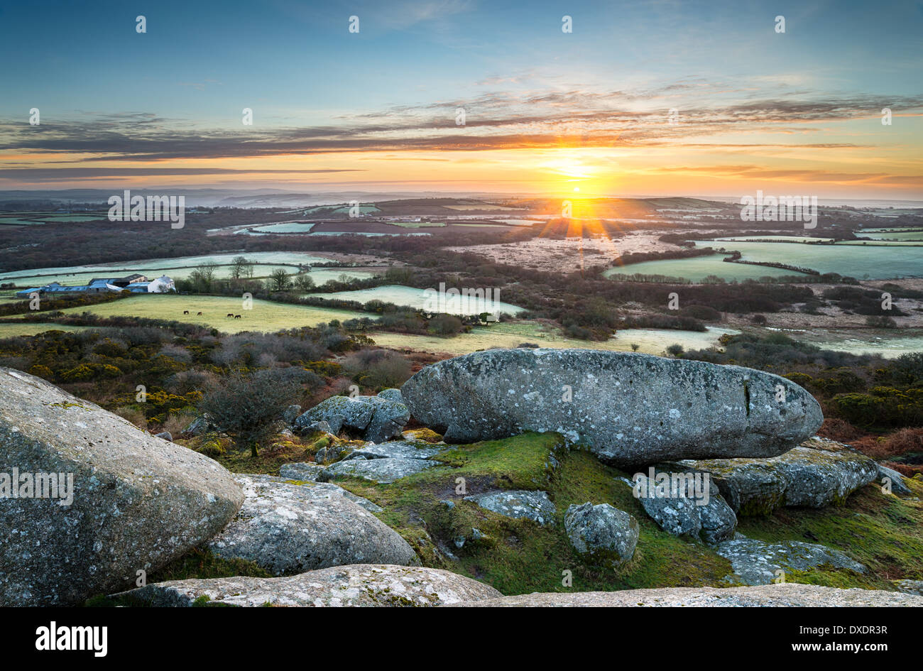 A frosty early spring sunrise looking out over a patchwork of fields and rolling hills at Helman Tor a rocky outcrop of rugged m Stock Photo