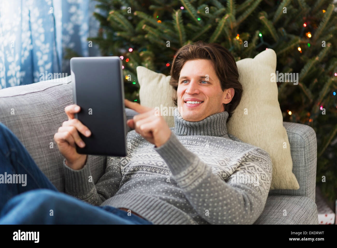 Man lying on sofa and using tablet Stock Photo