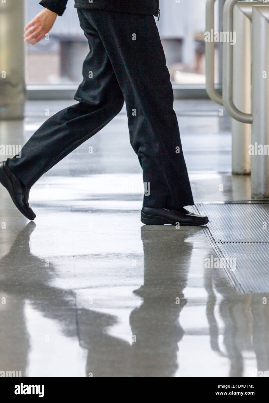 person walking quickly in public space with reflection in glossy floor