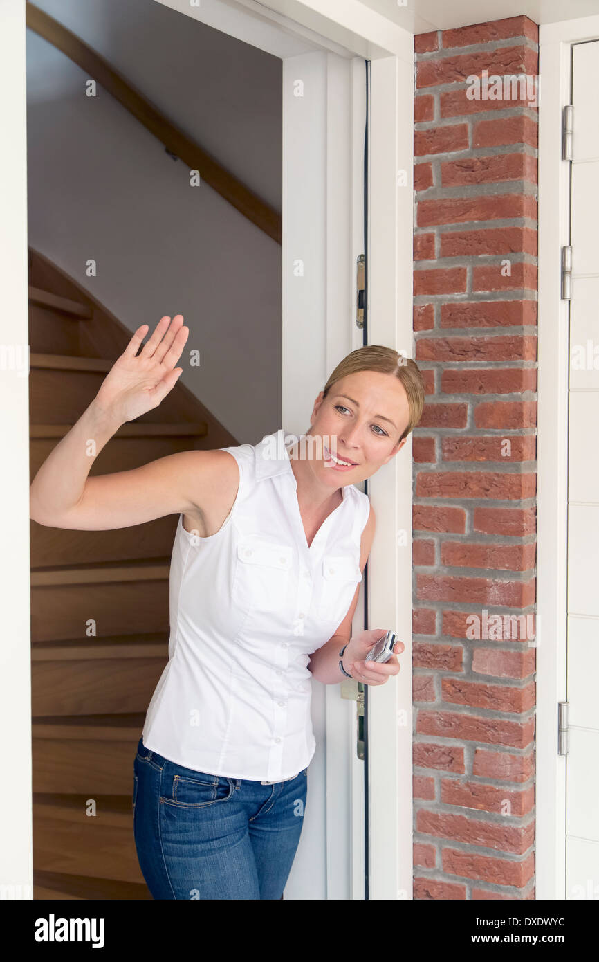 Woman opening door and waving Stock Photo - Alamy