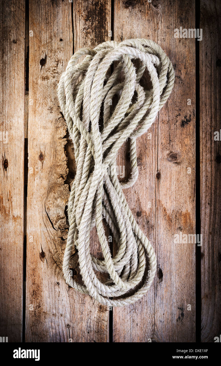 Old rope twisted and tied in a bundle on a rough wooden background ...