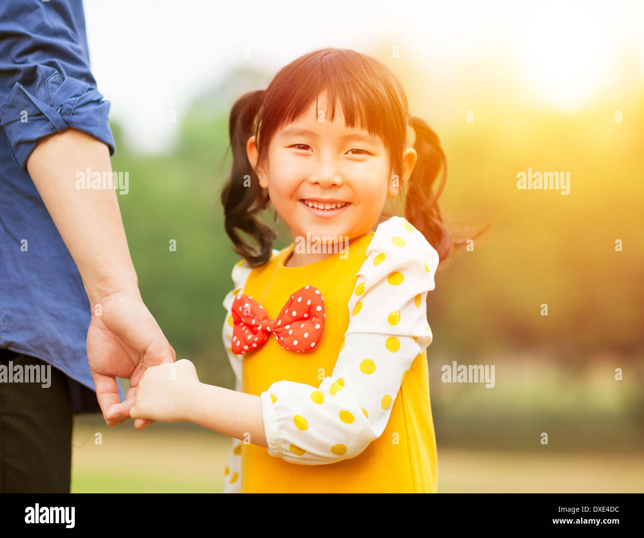 pretty girl hold father hand in the park with sunlight in the park ...