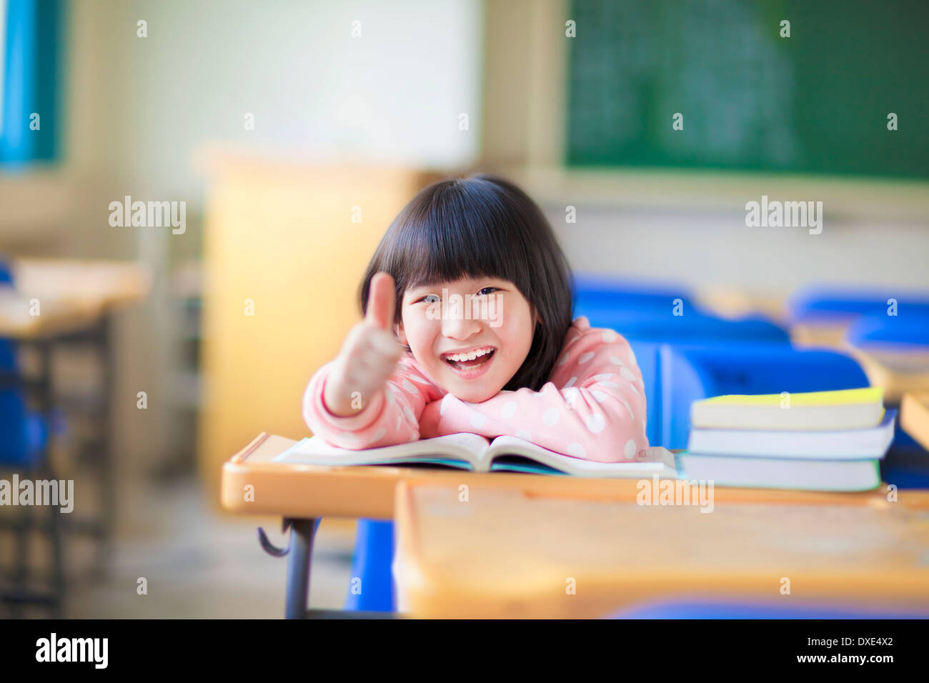happy kid thumb up with book in class Stock Photo