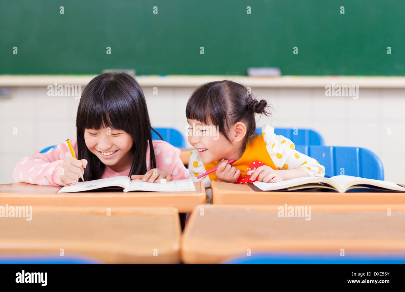 cute little student  look her classmate homework in a classroom Stock Photo