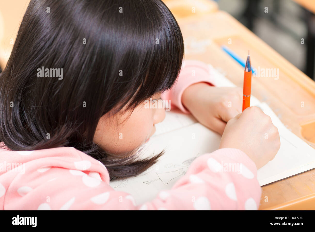student is focus on drawing his book in a classroom Stock Photo