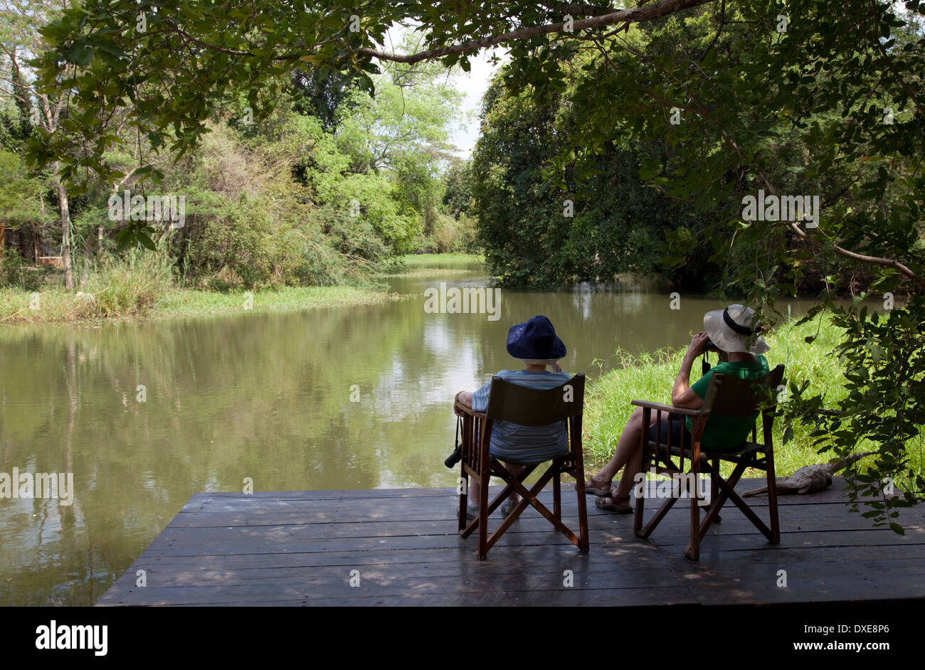 Two Tourists Relaxing In Chairs By Natural Pool Zambezi