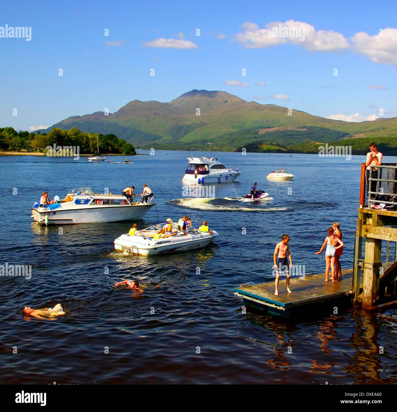 Busy summer scene around Luss pier with Ben Lomond in view, Dumbartonshire. Stock Photo