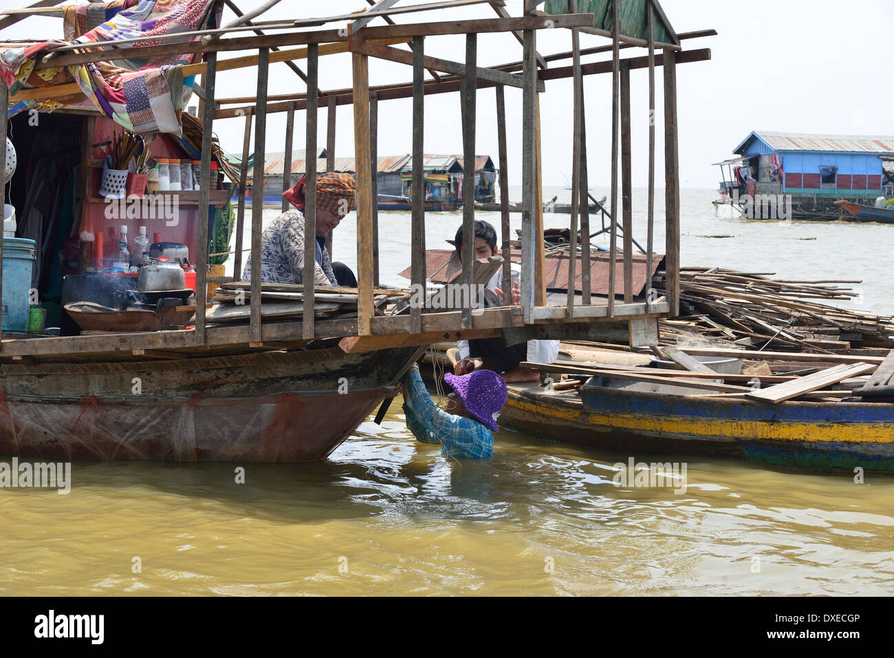 Man  in the water repairing his houseboat on Tonle Sap Lake in the  floating village, Cambodia, Southeast Asia Stock Photo