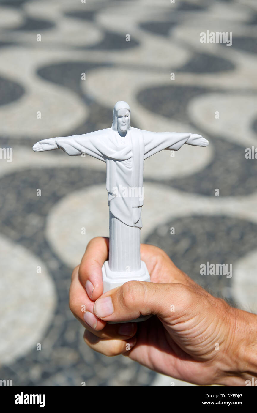 Tourist holding Corcovado Christ the Redeemer statue souvenir at Copacabana Beach boardwalk Rio de Janeiro Brazil Stock Photo