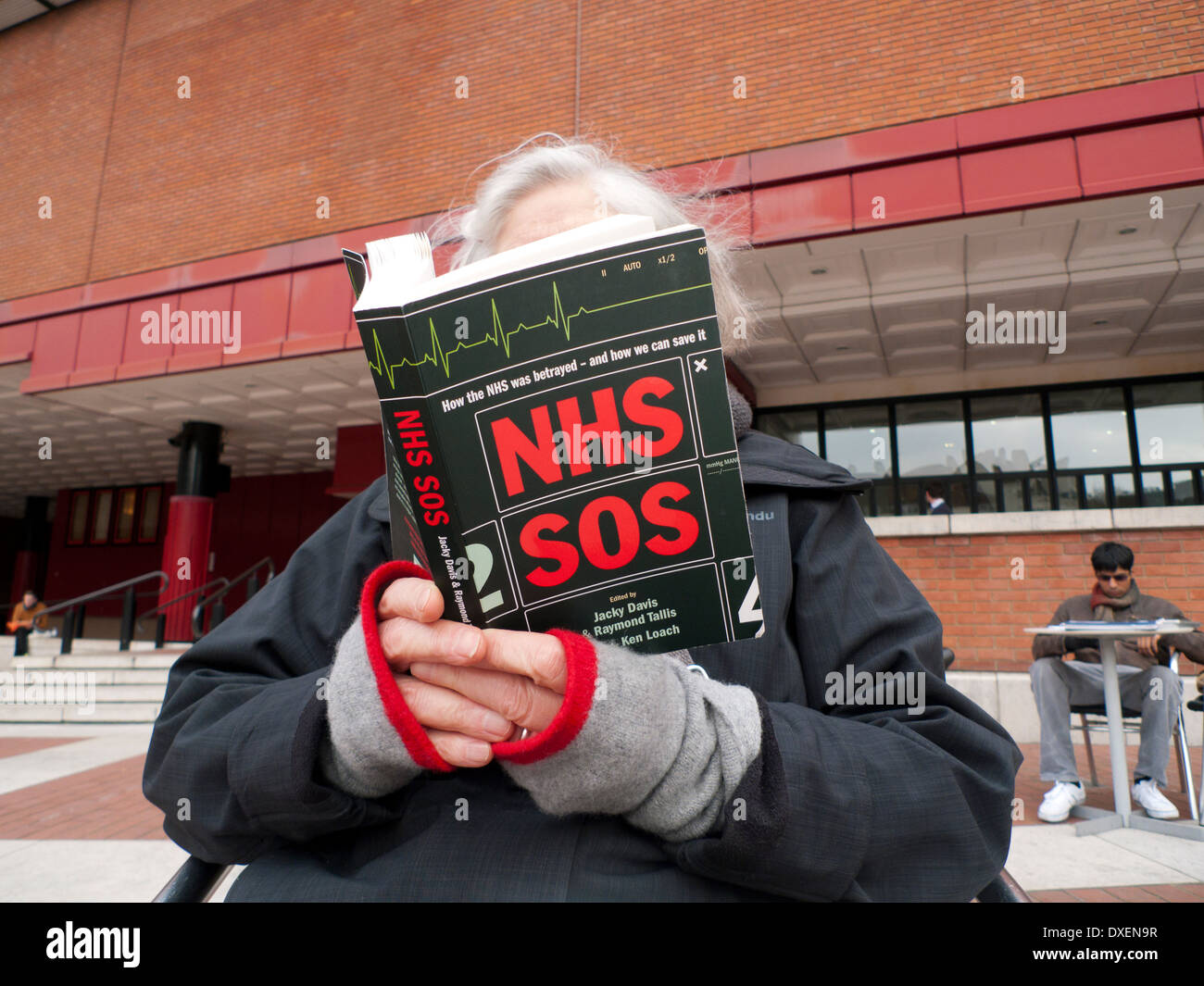 Woman reading NHS SOS book in the courtyard ot The British Library, Euston London England UK    KATHY DEWITT Stock Photo