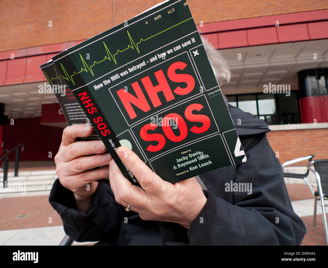 Woman reading NHS SOS book in the courtyard ot The British Library, Euston London England UK   KATHY DEWITT Stock Photo