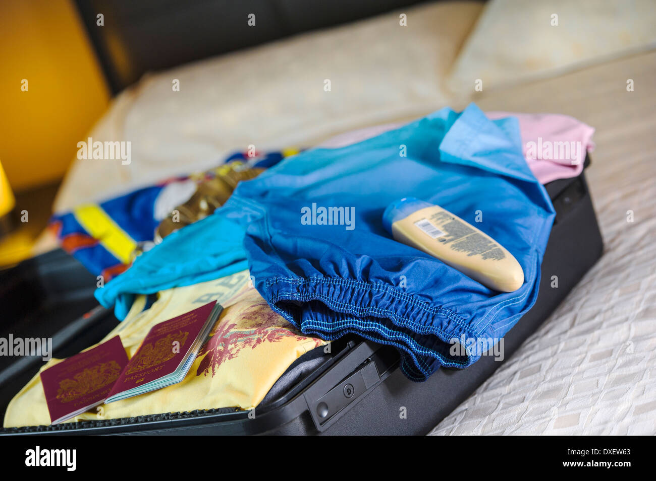 Holiday suitcase being unpacked in a hotel bedroom. Stock Photo