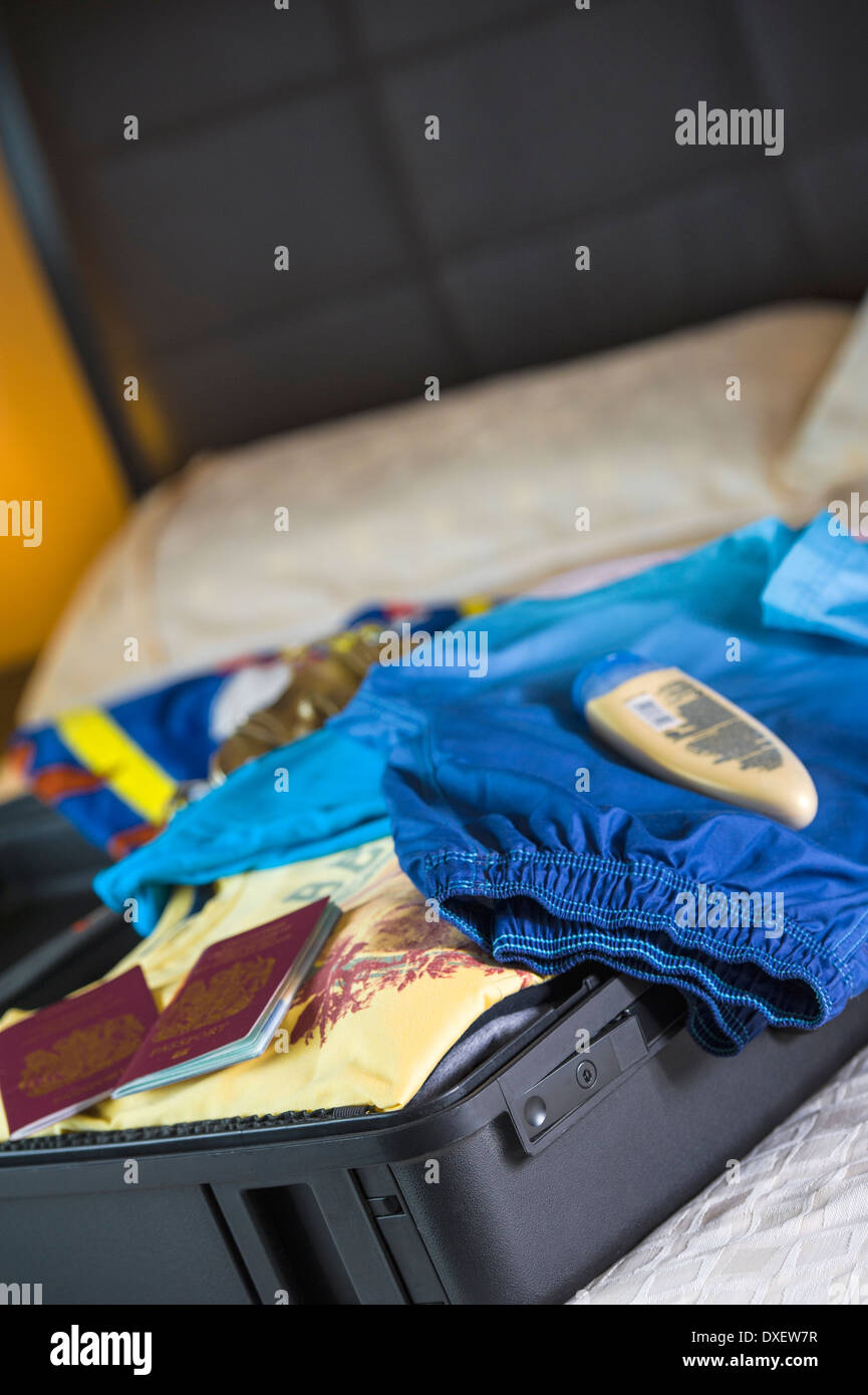 Holiday suitcase being unpacked in a hotel bedroom. Stock Photo