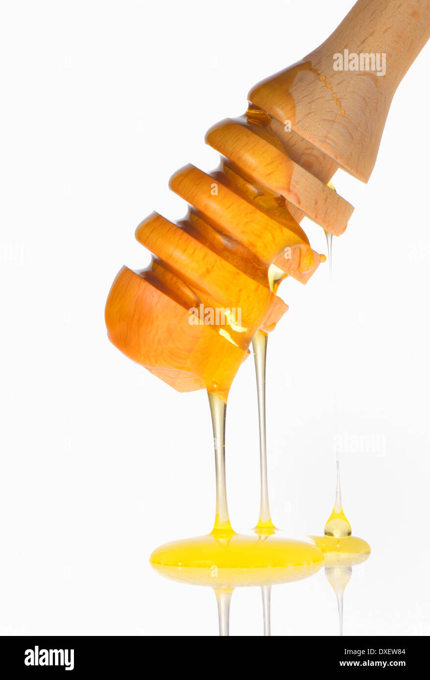 Honey dripping from a wooden honey dipper Stock Photo